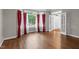 Living room with bright windows, red curtains, hardwood flooring, and a front door view at 105 Bathgate Ln, Cary, NC 27513