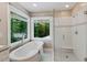 Bright bathroom features a soaking tub and glass-enclosed shower next to a window overlooking a wooded view at 105 Windfall Ct, Cary, NC 27518