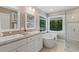 Bright bathroom with double vanity, soaking tub, and glass-enclosed shower by two windows offering wooded view at 105 Windfall Ct, Cary, NC 27518