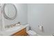 A half bath features a round mirror, vanity with sink, and toilet creating a functional space at 105 Windfall Ct, Cary, NC 27518
