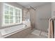 Relaxing bathroom featuring soaking tub, frameless shower, and large window at 10721 Marabou Ct, Raleigh, NC 27614
