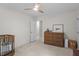 Neutral bedroom featuring a ceiling fan, wood dresser, baby bed, and an adjoining doorway at 10721 Marabou Ct, Raleigh, NC 27614