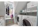 Bright laundry room featuring two white appliances, a window, shelves and cabinets for storage at 10721 Marabou Ct, Raleigh, NC 27614