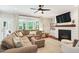 Inviting living room featuring a cozy fireplace, hardwood floors, ceiling fan and natural light at 108 Market Cross Ct, Holly Springs, NC 27540