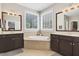 Well-lit main bathroom featuring double vanities and a jacuzzi tub for relaxation at 108 Market Cross Ct, Holly Springs, NC 27540