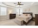 Cozy bedroom features a tray ceiling, ceiling fan, and large windows allowing for natural light at 108 Market Cross Ct, Holly Springs, NC 27540