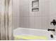 Tiled bathtub with modern black fixtures and tiled niches for storage at 110 Broadleaf Ln, Louisburg, NC 27549