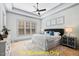 Inviting main bedroom with a tray ceiling, fan, and bright windows at 110 Broadleaf Ln, Louisburg, NC 27549