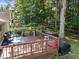 Wooden deck with seating and outdoor toys, surrounded by mature trees and lush greenery at 11901 N North Exeter Way Way, Raleigh, NC 27613