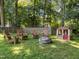 A backyard features seating, a fire pit, and playhouse, surrounded by trees at 11901 N North Exeter Way Way, Raleigh, NC 27613