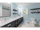 Bathroom with tile flooring, double sinks, mirrors, black cabinets, and light blue walls at 11901 N North Exeter Way Way, Raleigh, NC 27613