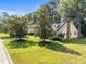 Inviting yellow home with manicured lawn and mature trees, complete with a brick chimney and cozy front porch at 11901 N North Exeter Way Way, Raleigh, NC 27613