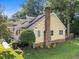 Beautiful yellow home featuring a brick chimney, mature landscaping, and a quaint front porch at 11901 N North Exeter Way Way, Raleigh, NC 27613