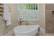 Modern bathroom featuring a soaking tub, stand-up shower, and lots of natural light from the window at 12201 Lockhart Ln, Raleigh, NC 27614