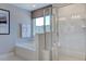Bright bathroom featuring a tub, glass enclosed shower, and neutral tiles at 124 Seagraves Creek Ln, Holly Springs, NC 27540
