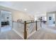 Bright upstairs hallway with neutral carpet, natural light, and wooden bannister at 124 Seagraves Creek Ln, Holly Springs, NC 27540