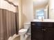 Charming bathroom featuring a dark vanity with a white sink and modern toilet next to a shower with neutral curtain at 12421 Angel Vale Pl, Durham, NC 27703