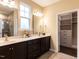 Bathroom with double vanity sinks, granite countertops, and a view of the walk-in closet at 12421 Angel Vale Pl, Durham, NC 27703