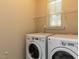 Functional laundry room featuring a washer and dryer with ample space for storage on overhead shelves at 12421 Angel Vale Pl, Durham, NC 27703