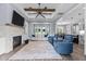 Open-concept living room with a stone fireplace, ceiling fan, and comfortable seating with view to the dining area at 125 Attena Way, Zebulon, NC 27597