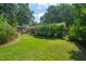 Spacious backyard featuring lush green grass, mature trees, and brick home at 1311 Norton St, Durham, NC 27701