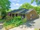 Beautiful brick home with lush front garden, black shutters, American flag, and a driveway leading to a back entrance at 1311 Norton St, Durham, NC 27701