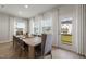 Dining area with a wooden table, white curtains, and a door leading to a green backyard at 1472 Hasse Ave, Apex, NC 27502
