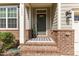 Inviting front porch with brick accents, a decorative wreath, and a cozy welcome mat at 1705 Bodwin Ln, Apex, NC 27502