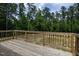 Back deck with wood floors and wood railing overlooking a green forest at 190 Whistlers Cv, Louisburg, NC 27549