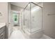 Bathroom with a large glass walk-in shower, white marbled tile, and storage shelving at 190 Whistlers Cv, Louisburg, NC 27549