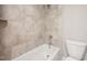 Tiled bathroom showcases a tub with shower and neutral earth-toned accents at 190 Whistlers Cv, Louisburg, NC 27549