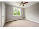 Cozy bedroom with neutral carpet, large window with lush greenery, and a ceiling fan at 190 Whistlers Cv, Louisburg, NC 27549