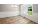 New dining room with wood-look flooring, wainscoting, modern chandelier, and large picture window at 190 Whistlers Cv, Louisburg, NC 27549