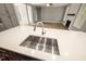 Kitchen island featuring white countertop, stainless steel sink and faucet with view to living room at 190 Whistlers Cv, Louisburg, NC 27549