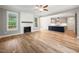 Open concept living room featuring fireplace with mantle, wood-look flooring, and view into kitchen at 190 Whistlers Cv, Louisburg, NC 27549
