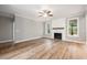 Spacious living room with wood floors, a ceiling fan, a fireplace and two windows at 190 Whistlers Cv, Louisburg, NC 27549
