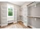 Custom walk-in closet with built-in shelving, wood floors, and a bright window at 190 Whistlers Cv, Louisburg, NC 27549