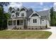 Inviting home exterior with stone accents and a covered porch, enhanced by lush green landscaping and blue sky at 200 Whistlers Cv, Louisburg, NC 27549