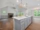 Open floor plan showcasing kitchen island with seating, modern lighting, stainless steel appliances, and fireplace at 200 Whistlers Cv, Louisburg, NC 27549