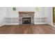 Living room features a stone fireplace with a wooden mantel, built-in bookshelves and hardwood floors at 200 Whistlers Cv, Louisburg, NC 27549
