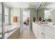 Well-lit bathroom featuring dual vanities, soaking tub, and open doorway to bedroom at 204 Towne Ridge Ln, Chapel Hill, NC 27516