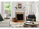 Cozy living room with a fireplace, hardwood floors, and natural light pouring through large windows at 204 Towne Ridge Ln, Chapel Hill, NC 27516