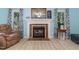 Living room featuring light blue walls, wood-look floors, and a brick fireplace with mantle at 204 Valley Ct, Selma, NC 27576