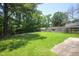 A spacious backyard featuring a green lawn, mature trees, and a wooden fence at 205 Cedar Dr, Zebulon, NC 27597
