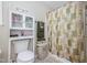 Cozy bathroom with a toilet, storage cabinet, shower with a patterned curtain, and soft neutral colors at 205 Cedar Dr, Zebulon, NC 27597