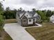 Aerial view of a house with a long driveway, lush green lawn, white siding, and stone accents at 225 Whistlers Cv, Louisburg, NC 27549