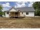 Backyard of a home with a large wooden deck and white siding, set against a backdrop of green trees at 225 Whistlers Cv, Louisburg, NC 27549