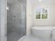 Elegant bathroom showcasing a glass shower, freestanding tub, and a window offering natural light at 225 Whistlers Cv, Louisburg, NC 27549