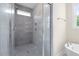 Modern bathroom featuring a glass-enclosed shower with gray tiling and a separate soaking tub near a window at 225 Whistlers Cv, Louisburg, NC 27549