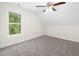 Sloped-ceiling bedroom with carpet, a ceiling fan, and a large window offering views of the surrounding green space at 225 Whistlers Cv, Louisburg, NC 27549